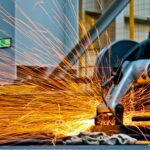 Lead Lined Drywall A worker operates a grinder cutting metal, creating a vibrant display of sparks in an industrial setting.